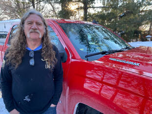 Paul from Minnetonka, a satisfied customer, stands next to his red truck.