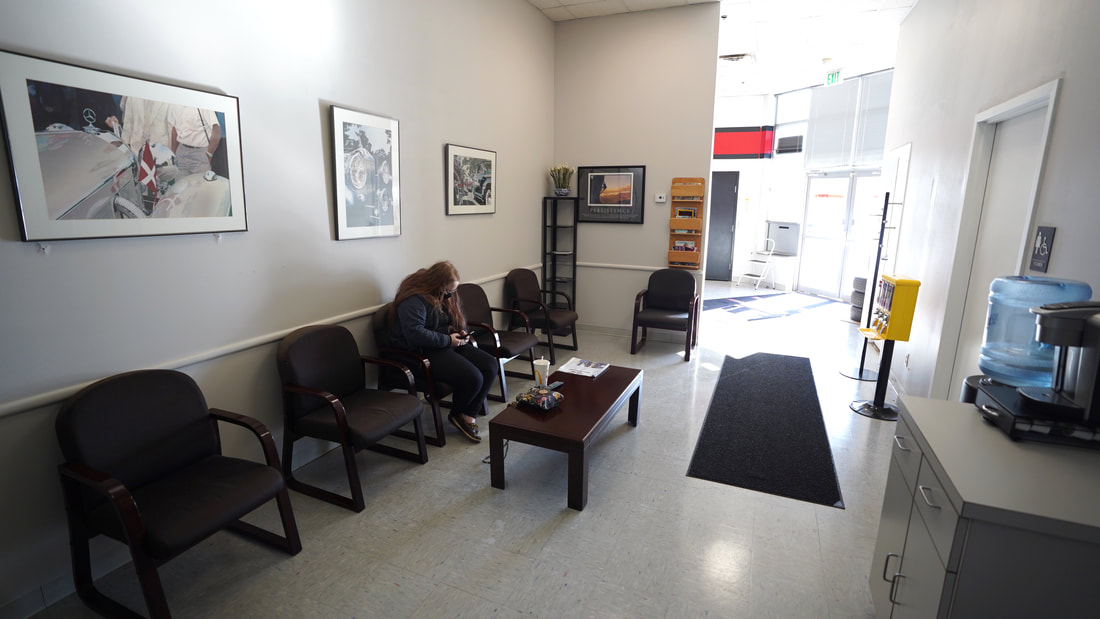 We see the spacious waiting room with pictures on the wall and one woman looking at her phone.