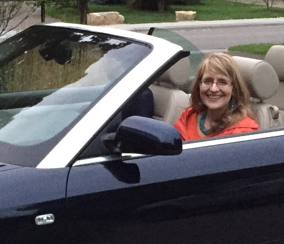Smith Nielsen customer, Linda from Edina, is seen smiling at the wheel of her convertible.