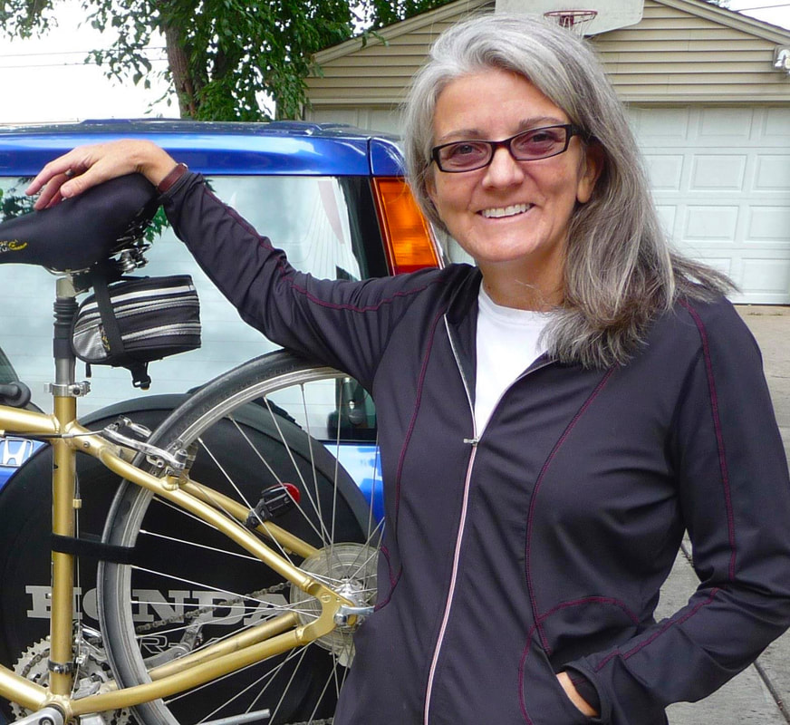 Pam from St. Louis Park stands behind her blue Honda CR-V, which has a bike rack on the back.